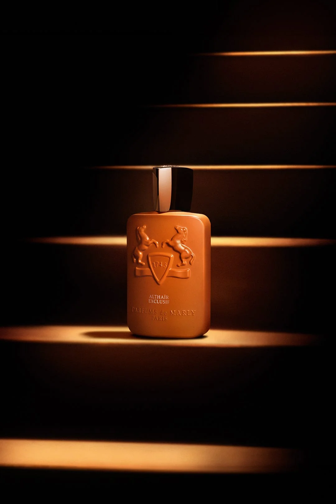 Brown perfume bottle with horse motifs set against illuminated stairs and dark background.