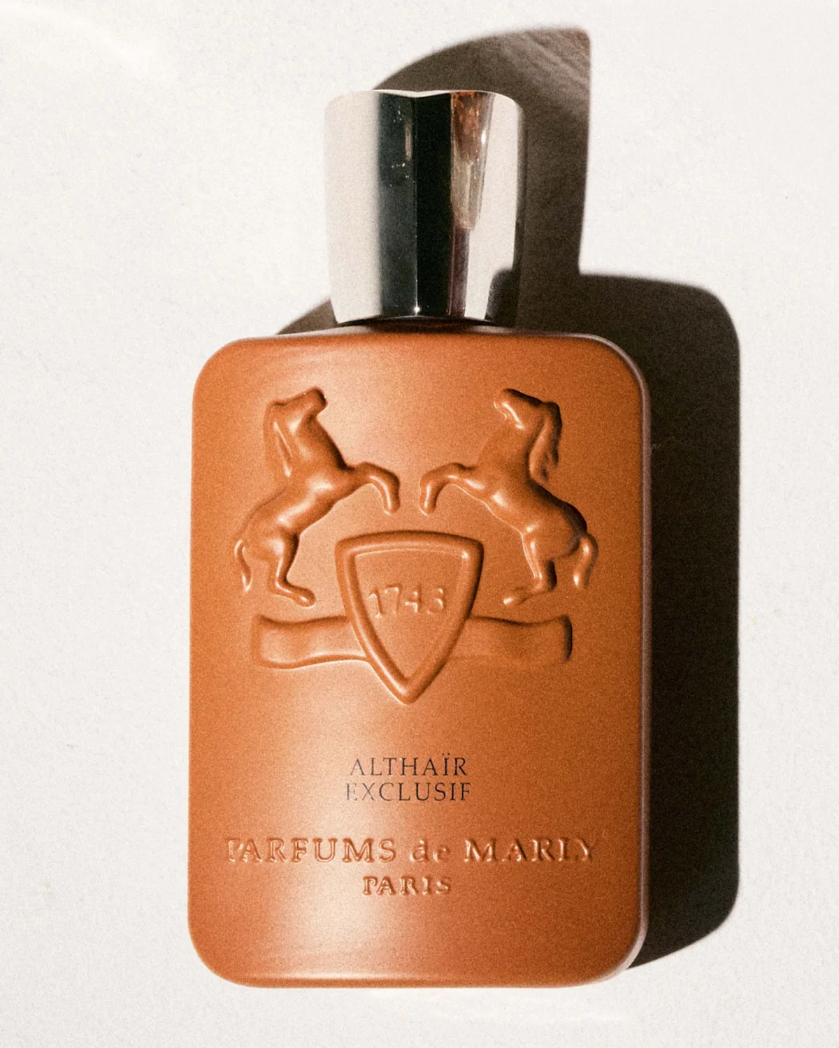 Brown perfume bottle with horse motif and silver cap, labeled "Althair Exclusif" by Parfums de Marly, Paris. Brown perfume bottle with horse motif and silver cap, labeled "Althair Exclusif" by Parfums de Marly, Paris.