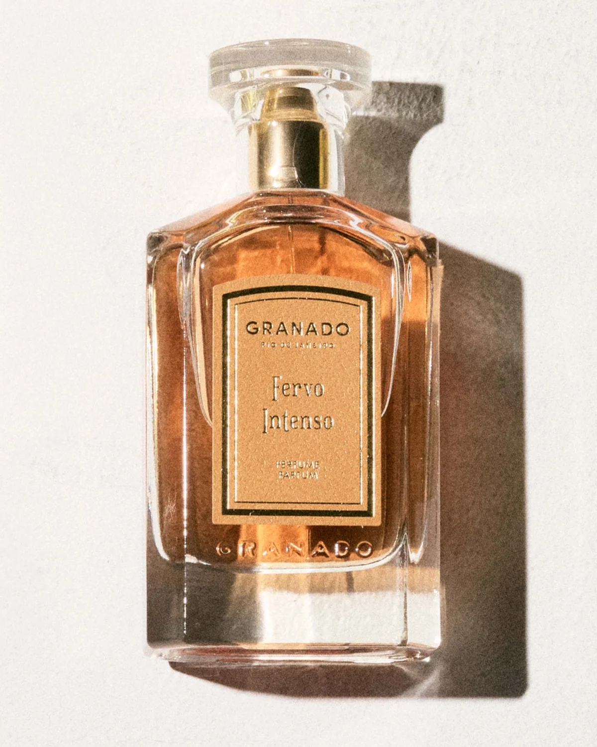 Granado Fervo Intenso perfume bottle with a golden label on a light background. Granado Fervo Intenso perfume bottle with a golden label on a light background.