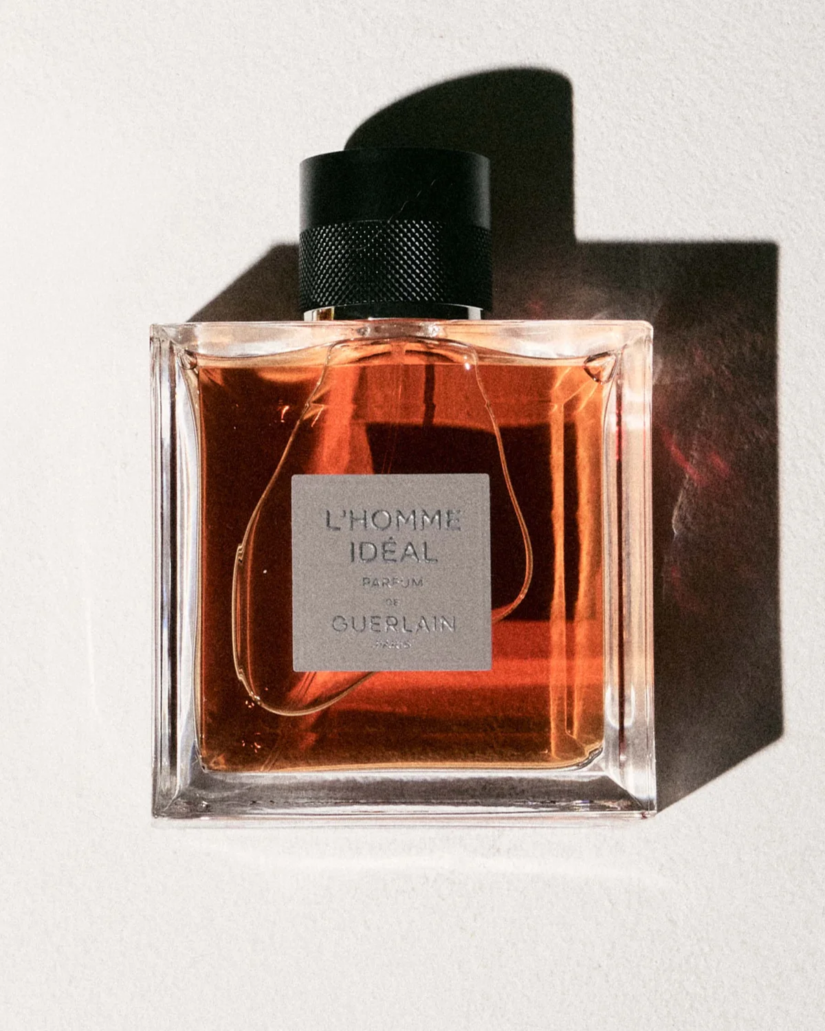 Bottle of L'Homme Idéal perfume by Guerlain with an amber liquid and a sleek design. Bottle of L'Homme Idéal perfume by Guerlain with an amber liquid and a sleek design.