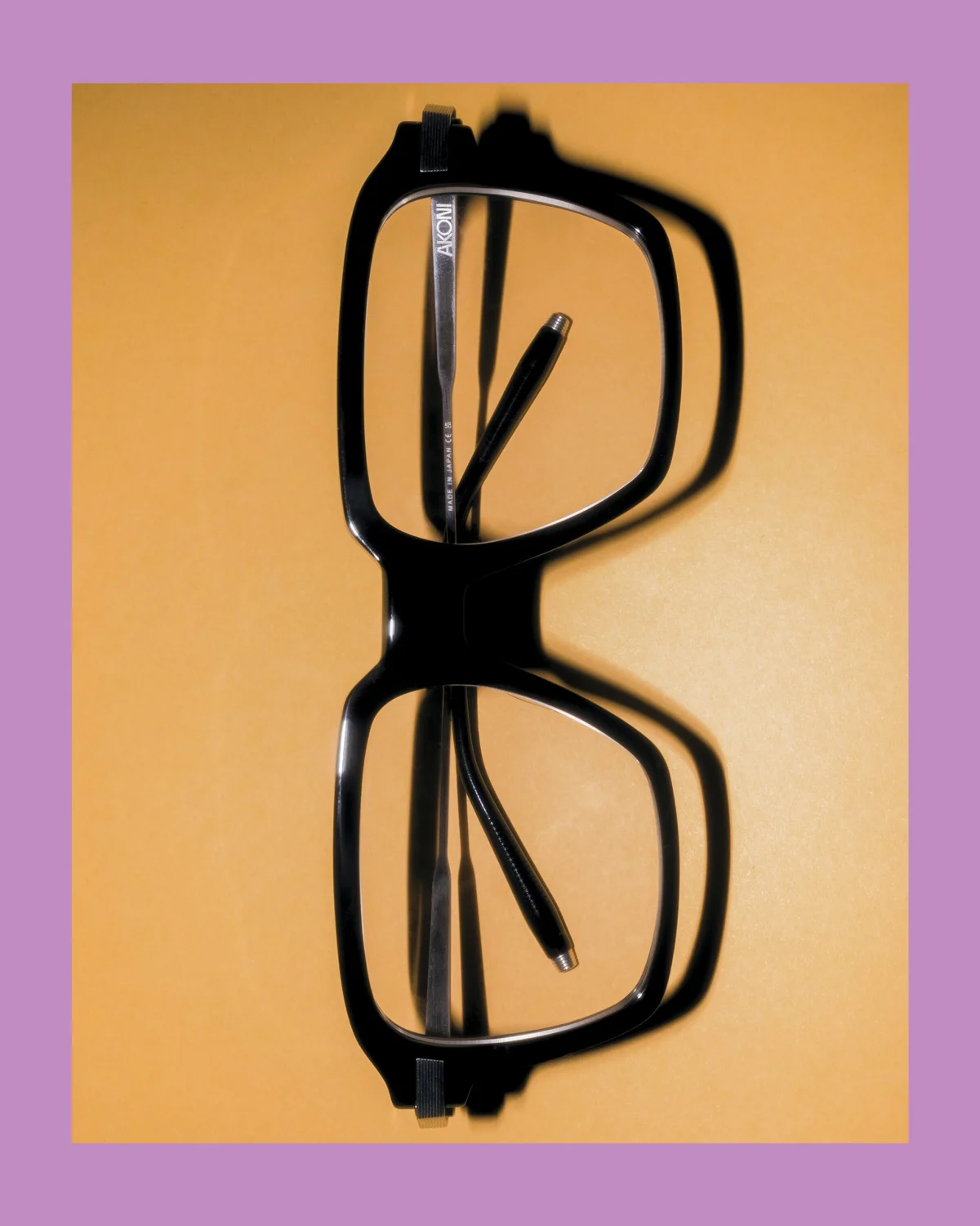 Black oversized eyeglasses with a stylish design on a yellow background.