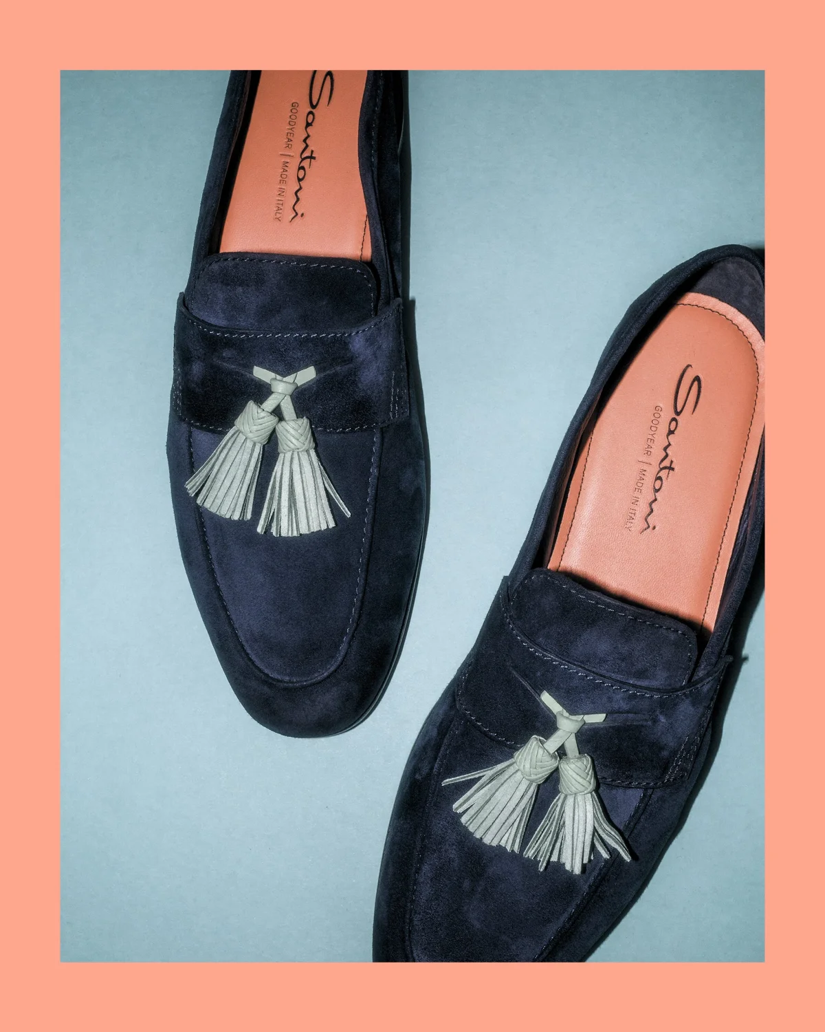 Deep blue suede loafers with a tassel detail and an orange insole.